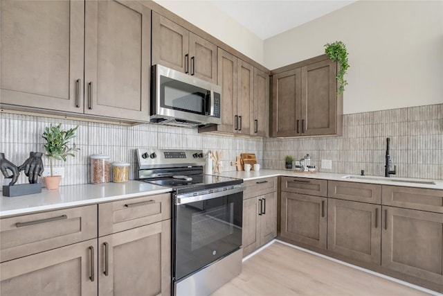2309 Montopolis Dr Unit 8, Austin, TX 78741 - kitchen featuring appliances with stainless steel finishes, backsplash, light wood finished floors, and light countertops