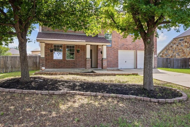383 Spring Dr, Kyle, TX 78640 - obstructed view of property with driveway, brick siding, a garage, and covered porch