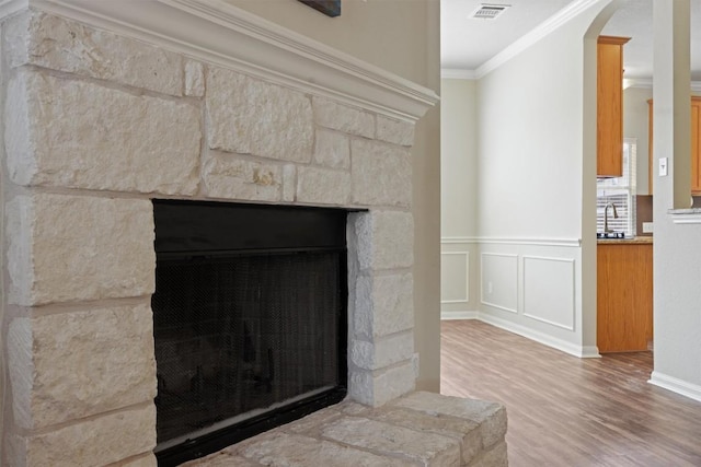 383 Spring Dr, Kyle, TX 78640 - detailed view of crown molding, wood finished floors, arched walkways, a stone fireplace, and a sink