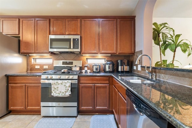 620 Allens Creek Way, Round Rock, TX 78664 - kitchen featuring stainless steel appliances, dark stone countertops, tasteful backsplash, brown cabinets, and light tile patterned floors