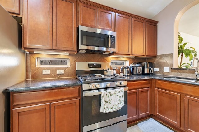 620 Allens Creek Way, Round Rock, TX 78664 - kitchen with stainless steel appliances, arched walkways, tasteful backsplash, and brown cabinets