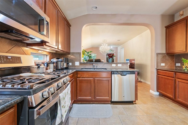 620 Allens Creek Way, Round Rock, TX 78664 - kitchen with stainless steel appliances, arched walkways, lofted ceiling, brown cabinets, and tasteful backsplash