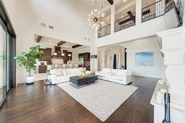 8100 Magnolia Ridge Cv, Austin, TX 78738 - living room featuring arched walkways, dark wood-type flooring, baseboards, a towering ceiling, and a chandelier
