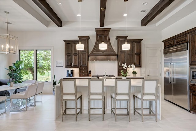 8100 Magnolia Ridge Cv, Austin, TX 78738 - kitchen with built in appliances, beamed ceiling, a kitchen island with sink, dark brown cabinets, and light countertops