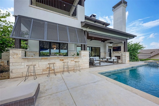 8100 Magnolia Ridge Cv, Austin, TX 78738 - rear view of property with an outdoor bar, stone siding, a patio, a chimney, and an outdoor living space with a fireplace
