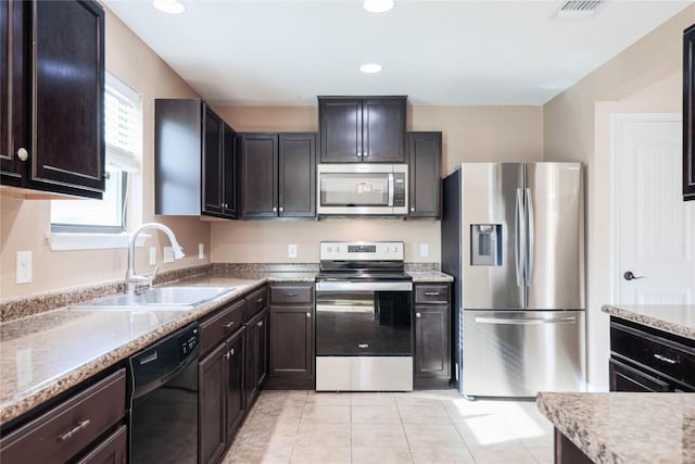 9001 Edmundsbury Dr, Austin, TX 78747 - kitchen featuring appliances with stainless steel finishes, a sink, light tile patterned flooring, dark brown cabinets, and recessed lighting