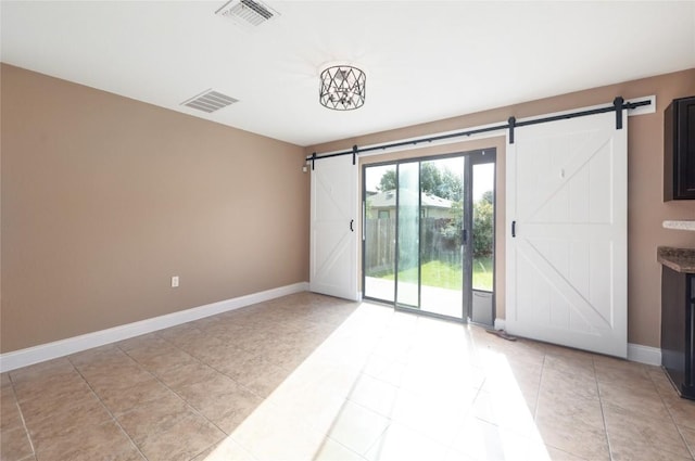 9001 Edmundsbury Dr, Austin, TX 78747 - empty room featuring a barn door, light tile patterned flooring, and baseboards