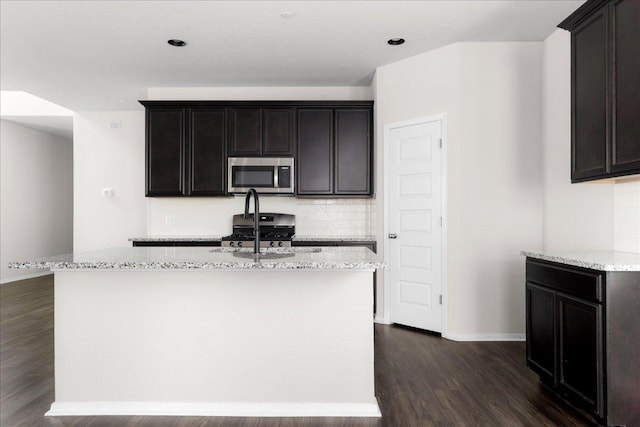 2800 Joe Dimaggio Blvd Unit 100, Round Rock, TX 78665 - kitchen featuring appliances with stainless steel finishes, dark wood finished floors, tasteful backsplash, and light stone counters