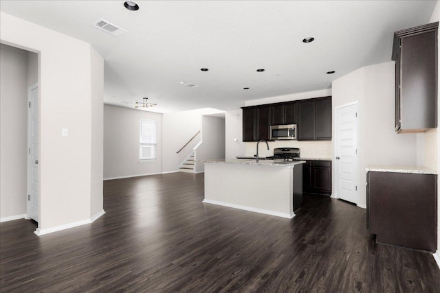 2800 Joe Dimaggio Blvd Unit 100, Round Rock, TX 78665 - kitchen with stainless steel microwave, open floor plan, dark wood-style flooring, range, and a center island with sink