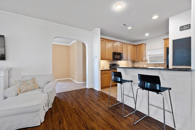 1813 Indian Lodge Dr, Cedar Park, TX 78613 - kitchen with black microwave, a breakfast bar area, dark wood-style flooring, backsplash, and arched walkways