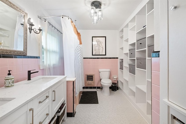 1003 E 13th St Unit 1, Austin, TX 78702 - bathroom featuring tile walls, heating unit, toilet, double vanity, and wainscoting