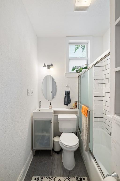 1003 E 13th St Unit 1, Austin, TX 78702 - bathroom featuring enclosed tub / shower combo, vanity, toilet, and baseboards