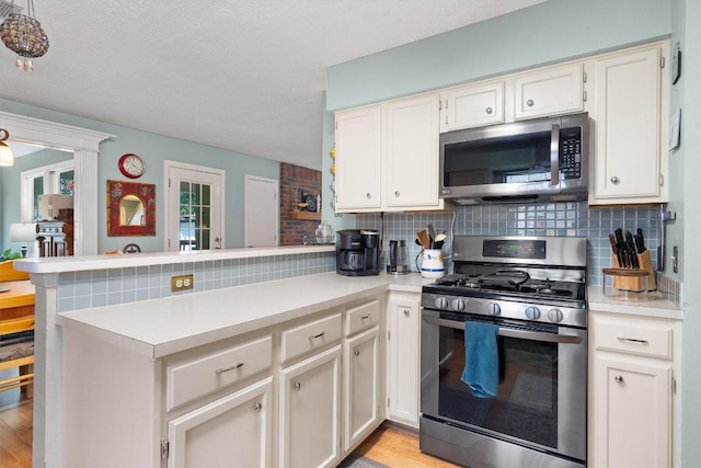 534 Broken Feather Trl, Pflugerville, TX 78660 - kitchen featuring stainless steel appliances, a peninsula, backsplash, light countertops, and light wood-style flooring