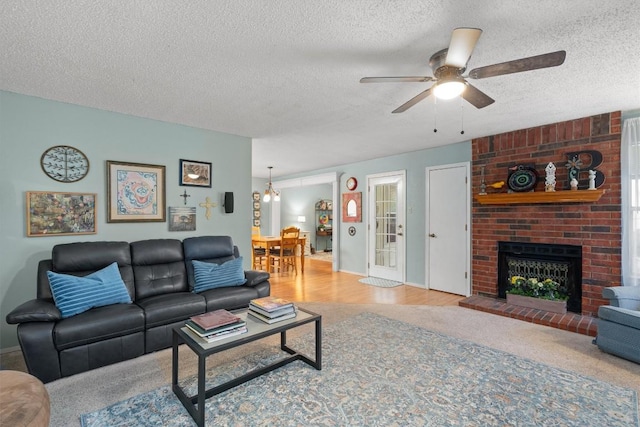 534 Broken Feather Trl, Pflugerville, TX 78660 - carpeted living room featuring ceiling fan, a textured ceiling, and a fireplace