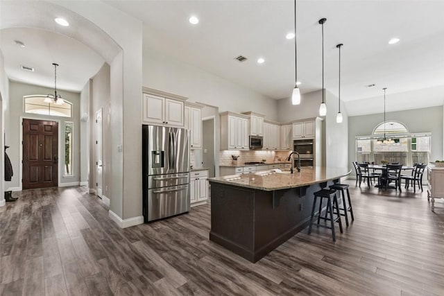 104 Blue Agave Ln, Georgetown, TX 78626 - kitchen featuring stainless steel appliances, cream cabinets, dark wood-type flooring, light stone counters, and baseboards