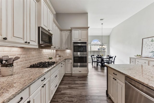 104 Blue Agave Ln, Georgetown, TX 78626 - kitchen with stainless steel appliances, dark wood-style floors, tasteful backsplash, light stone counters, and hanging light fixtures