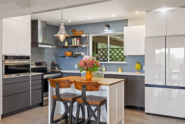 108 Highlander St, Lakeway, TX 78734 - kitchen featuring appliances with stainless steel finishes, wall chimney range hood, white cabinets, decorative backsplash, and a breakfast bar area