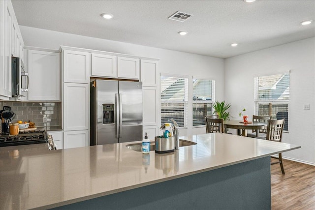 1725 Cobblecrest Ln, Leander, TX 78641 - kitchen featuring appliances with stainless steel finishes, healthy amount of natural light, white cabinetry, decorative backsplash, and recessed lighting