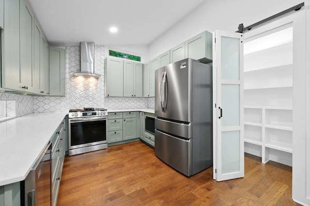 1006 Chericoo St, Austin, TX 78702 - kitchen featuring appliances with stainless steel finishes, wall chimney exhaust hood, dark wood-style floors, backsplash, and recessed lighting