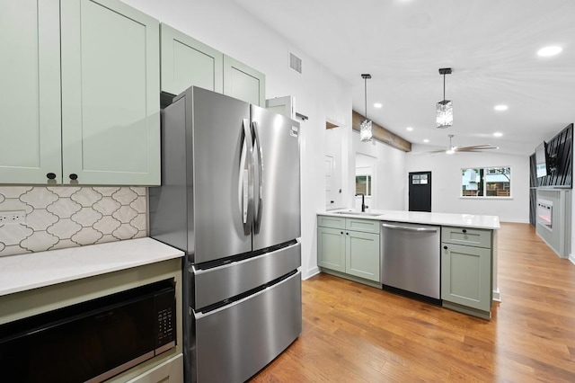 1006 Chericoo St, Austin, TX 78702 - kitchen featuring appliances with stainless steel finishes, a peninsula, recessed lighting, backsplash, and light wood-style flooring