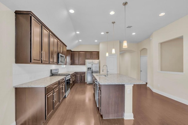 3546 Guadalajara St, Round Rock, TX 78665 - kitchen featuring appliances with stainless steel finishes, arched walkways, dark wood-style floors, tasteful backsplash, and light stone counters