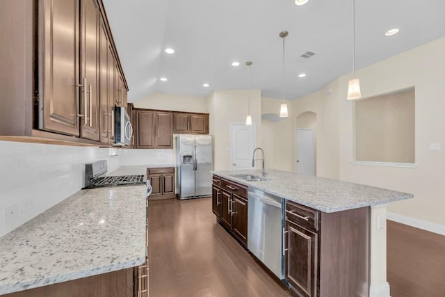 3546 Guadalajara St, Round Rock, TX 78665 - kitchen featuring appliances with stainless steel finishes, arched walkways, decorative backsplash, light stone countertops, and lofted ceiling