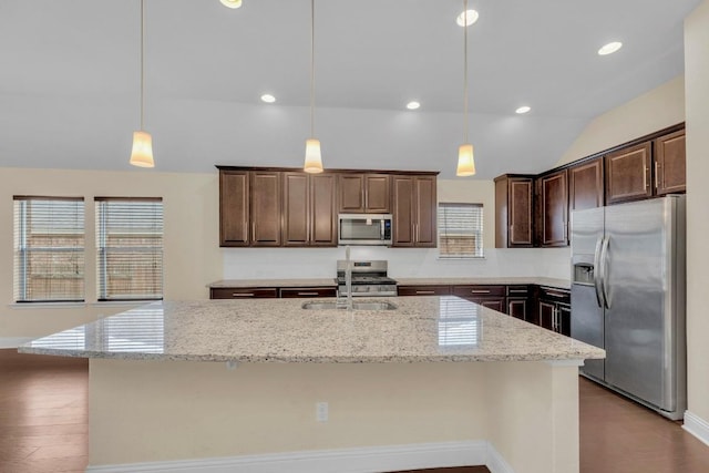 3546 Guadalajara St, Round Rock, TX 78665 - kitchen featuring appliances with stainless steel finishes, lofted ceiling, dark brown cabinetry, light stone counters, and a center island with sink
