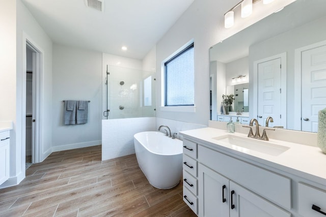 471 Diamondleaf Dr, Buda, TX 78610 - bathroom featuring vanity, a stall shower, wood finished floors, a freestanding bath, and recessed lighting