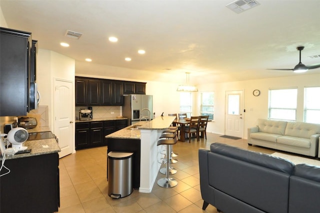 16805 Ruggio Rd, Pflugerville, TX 78660 - kitchen featuring open floor plan, refrigerator with ice dispenser, a breakfast bar area, backsplash, and recessed lighting