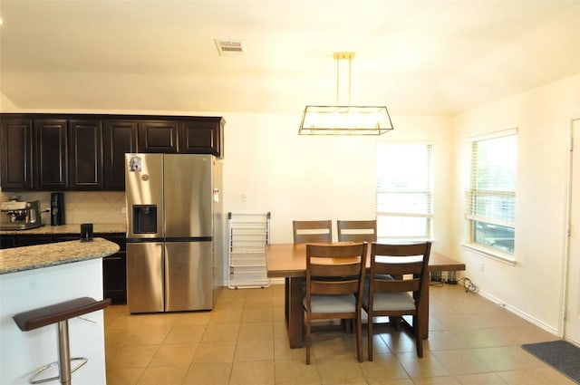 16805 Ruggio Rd, Pflugerville, TX 78660 - kitchen with stainless steel refrigerator with ice dispenser, light tile patterned flooring, light stone counters, and decorative light fixtures