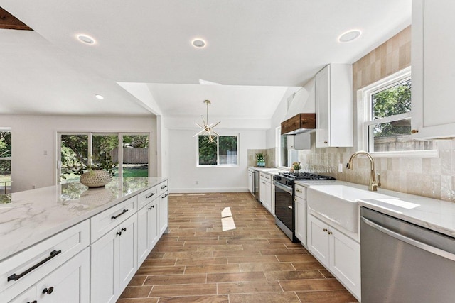 1111 Spearson Ln, Austin, TX 78745 - kitchen featuring appliances with stainless steel finishes, backsplash, white cabinets, recessed lighting, and vaulted ceiling