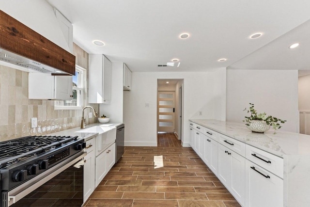 1111 Spearson Ln, Austin, TX 78745 - kitchen featuring appliances with stainless steel finishes, premium range hood, a peninsula, light stone counters, and tasteful backsplash