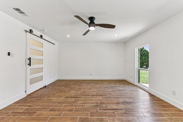 1111 Spearson Ln, Austin, TX 78745 - spare room with a barn door, ceiling fan, wood finished floors, and recessed lighting