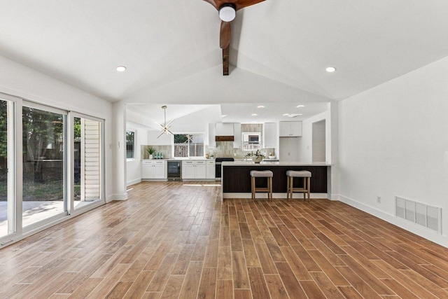 1111 Spearson Ln, Austin, TX 78745 - unfurnished living room with beverage cooler, light wood-style floors, recessed lighting, and a chandelier
