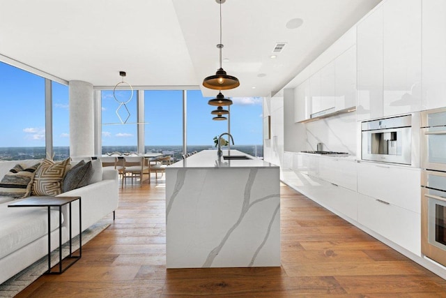 44 E Ave Unit 4603, Austin, TX 78701 - kitchen featuring modern cabinets, a sink, white cabinetry, light wood-style flooring, and oven