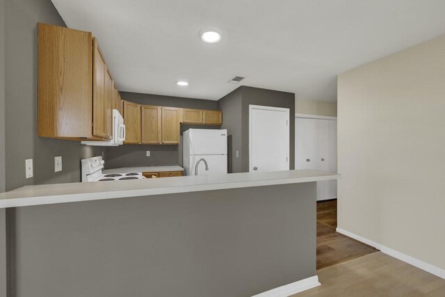1219 Canyon Trce, Canyon Lake, TX 78133 - kitchen with white appliances, a peninsula, light countertops, light wood-type flooring, and recessed lighting