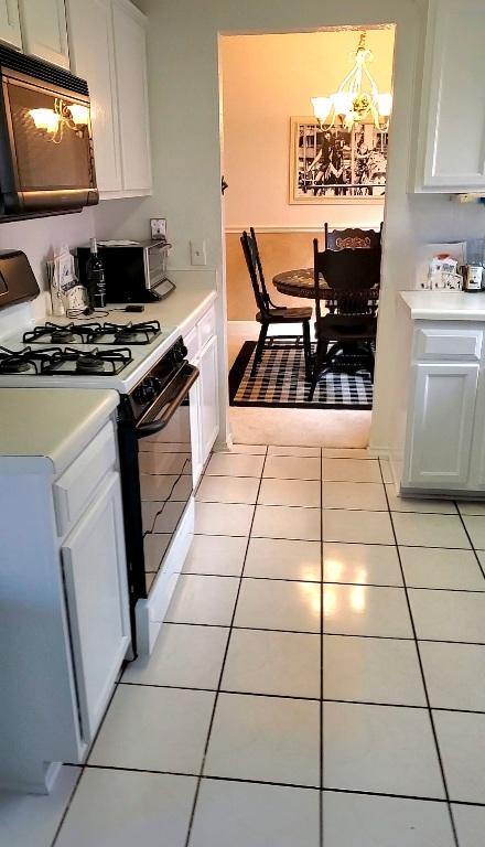 507 Dusty Leather Ct, Pflugerville, TX 78660 - kitchen with gas stove, a chandelier, light countertops, and light tile patterned flooring
