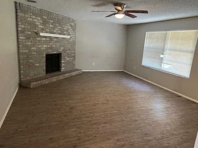 1010 Wayne Dr, Round Rock, TX 78664 - unfurnished living room with a ceiling fan, dark wood finished floors, a textured ceiling, and a brick fireplace