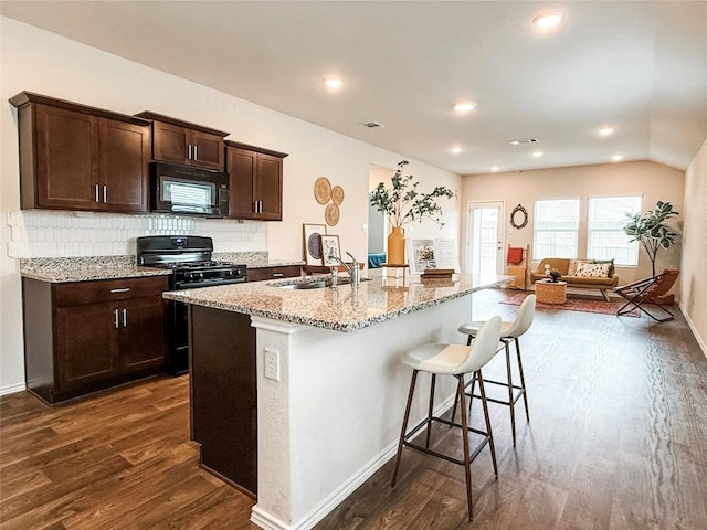 101 Calgary Ln, San Marcos, TX 78666 - kitchen featuring black appliances, dark wood finished floors, light stone countertops, a breakfast bar, and dark brown cabinets