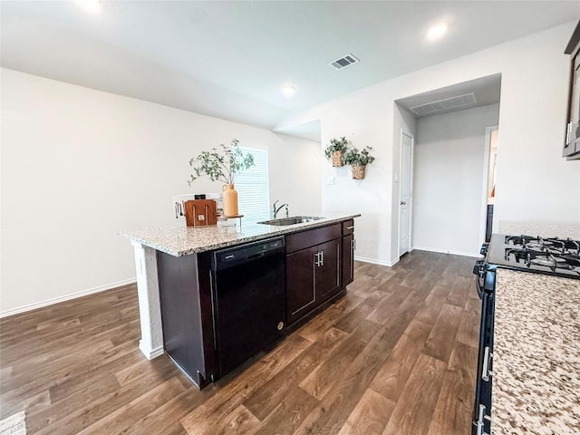 101 Calgary Ln, San Marcos, TX 78666 - kitchen with dishwasher, range with gas cooktop, dark wood finished floors, a kitchen island with sink, and light stone countertops