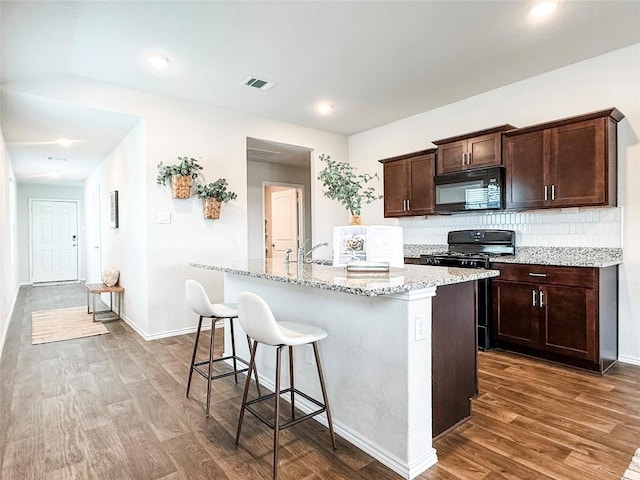 101 Calgary Ln, San Marcos, TX 78666 - kitchen with black appliances, dark wood finished floors, a kitchen bar, and tasteful backsplash