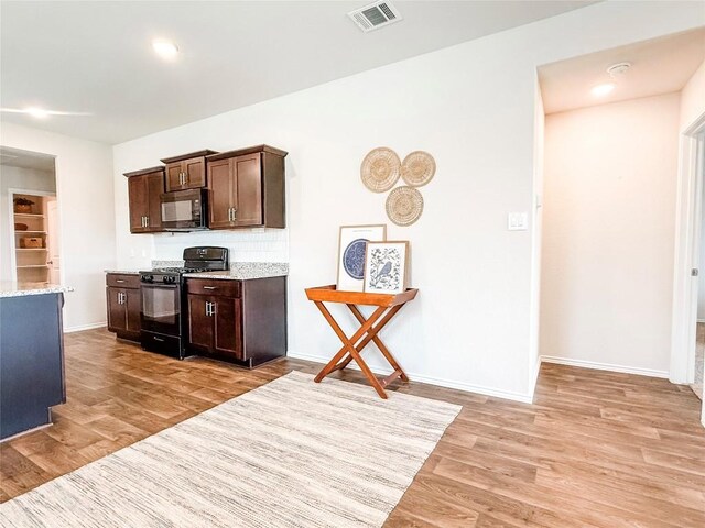 101 Calgary Ln, San Marcos, TX 78666 - kitchen with black appliances, light wood-style floors, dark brown cabinets, light stone countertops, and recessed lighting