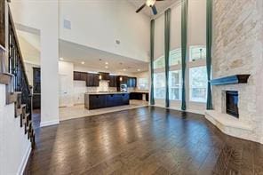 321 Navigator Dr, Austin, TX 78717 - unfurnished living room featuring dark wood-style flooring, a ceiling fan, a high ceiling, a fireplace, and stairs