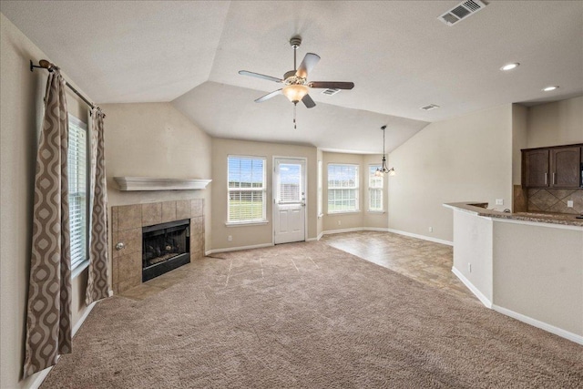 14513 Martial Eagle Dr, Elgin, TX 78621 - unfurnished living room featuring lofted ceiling, light carpet, ceiling fan, a tiled fireplace, and a chandelier