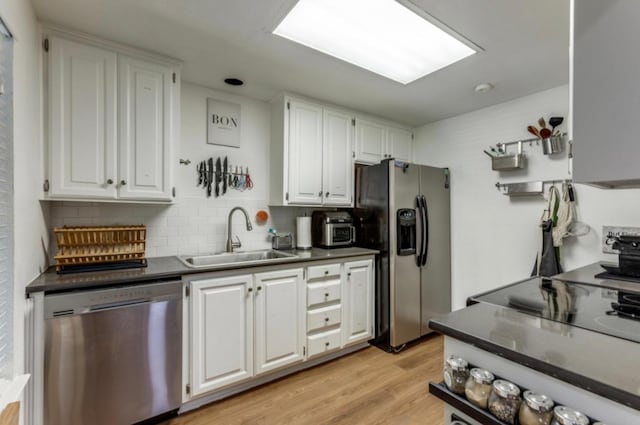 2529 Rio Grande St Unit 51, Austin, TX 78705 - kitchen featuring appliances with stainless steel finishes, white cabinets, decorative backsplash, dark countertops, and light wood finished floors