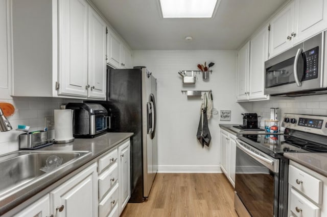2529 Rio Grande St Unit 51, Austin, TX 78705 - kitchen featuring appliances with stainless steel finishes, white cabinetry, backsplash, and light wood finished floors