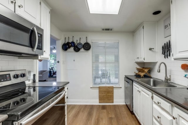 2529 Rio Grande St Unit 51, Austin, TX 78705 - kitchen featuring stainless steel appliances, a sink, dark countertops, white cabinets, and decorative backsplash