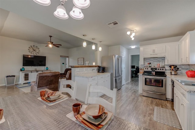 700 Indian Blanket St, Lockhart, TX 78644 - kitchen featuring appliances with stainless steel finishes, light wood finished floors, backsplash, white cabinets, and ceiling fan