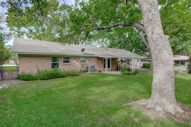 2502 Greenlawn Pkwy, Austin, TX 78757 - back of property with central AC, a lawn, brick siding, a gate, and a shingled roof