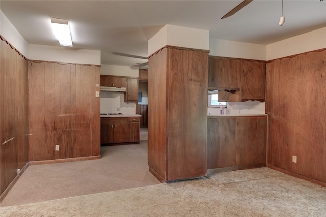 2502 Greenlawn Pkwy, Austin, TX 78757 - kitchen with under cabinet range hood, a ceiling fan, light carpet, and brown cabinetry